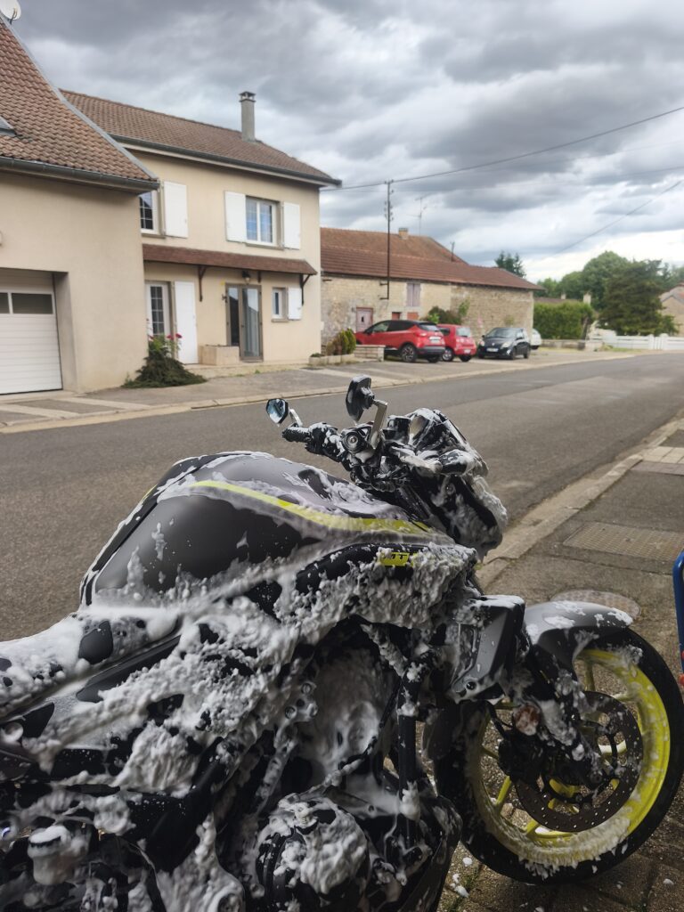 Vue rapprochée d'une moto Yamaha MT-03 recouverte d'une épaisse couche de mousse active blanche.